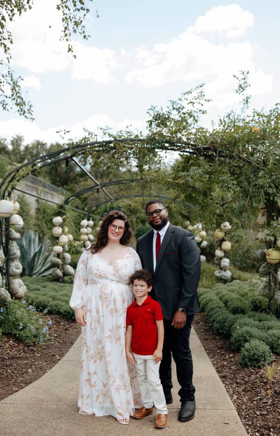 Hailey, Tristan and their son standing together on a garden path