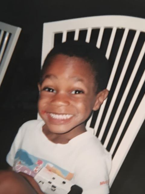 Tristan as a young boy, grinning in a white shirt
