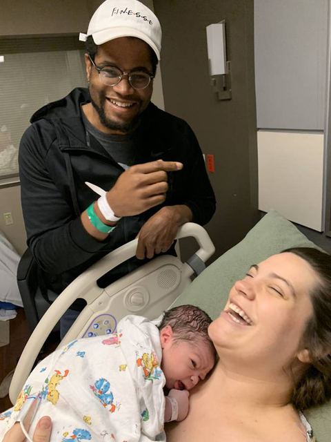 Tristan cradling their newborn beside Hailey laughing in the hospital
